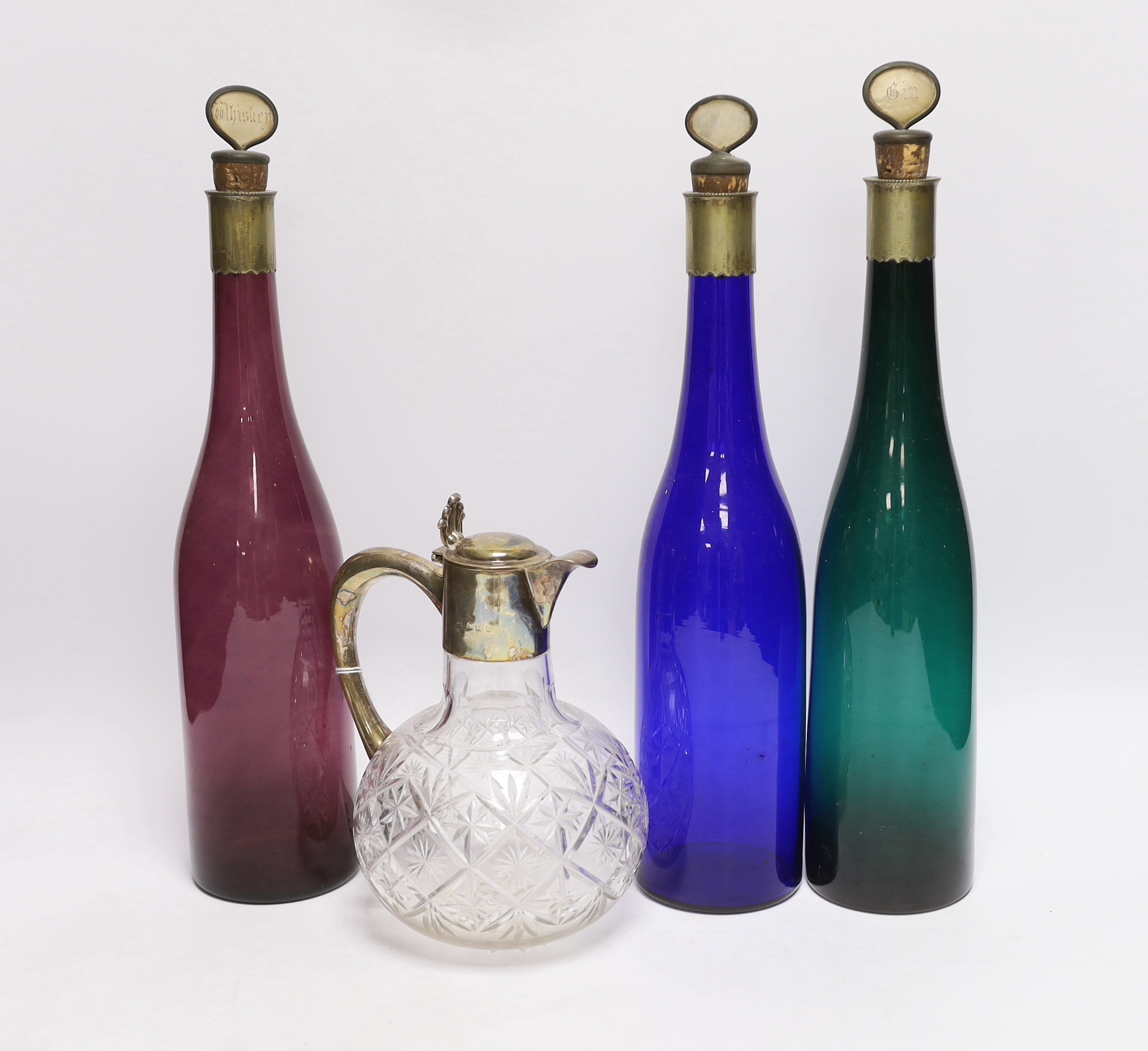 A silver mounted glass claret jug and three coloured glass bottles, 37cm